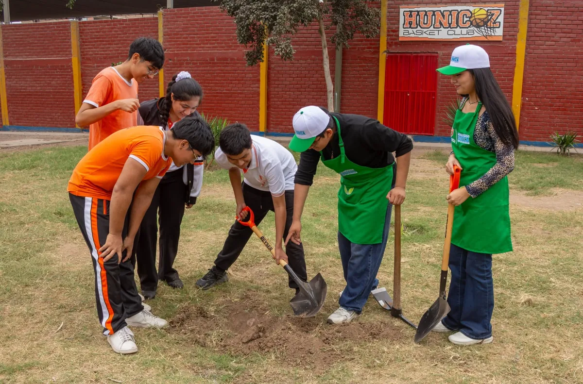 Estudiantes plantando un árbol con el equipo de la actividad