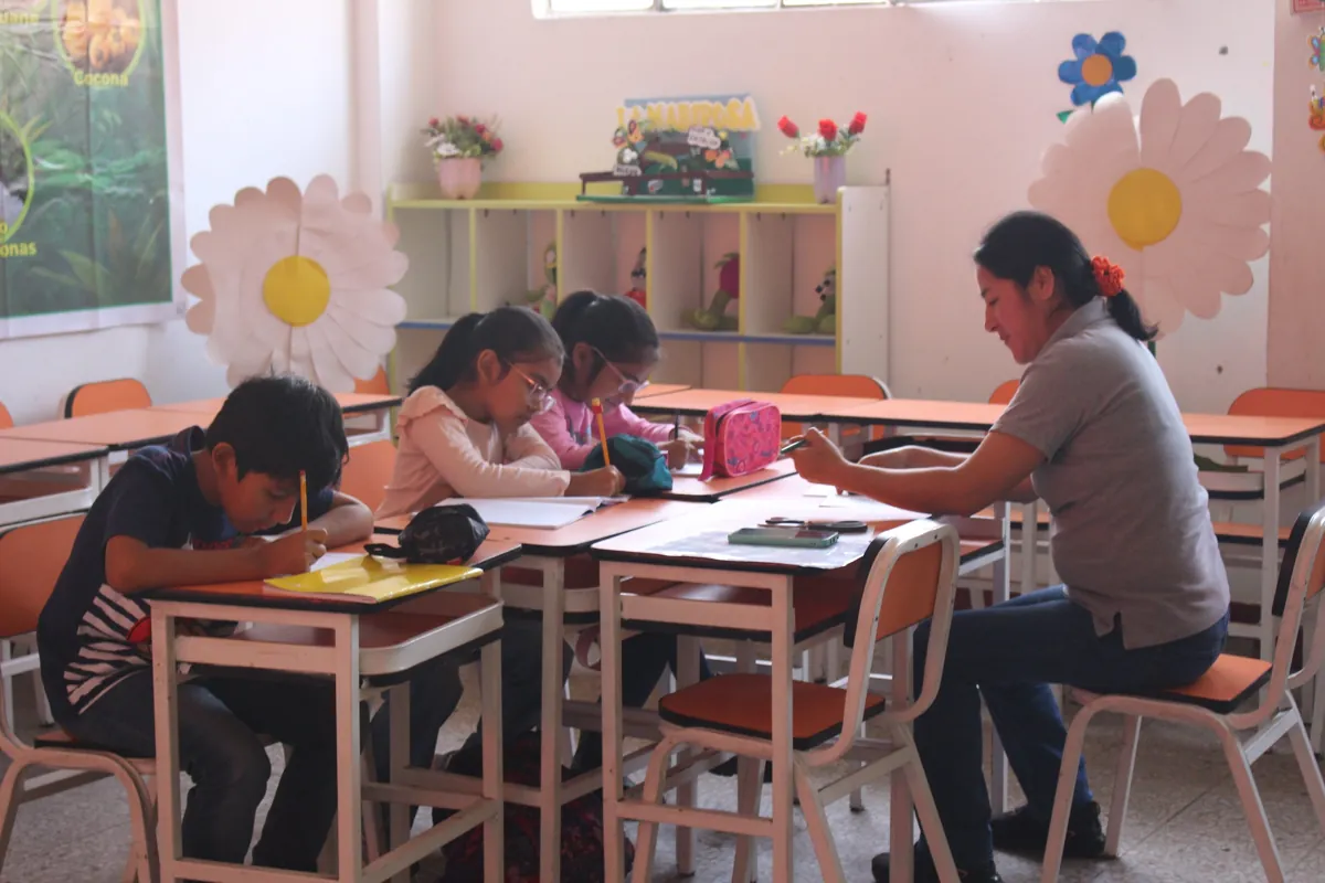 Estudiantes de Primaria trabajando en grupo con su docente en un taller académico