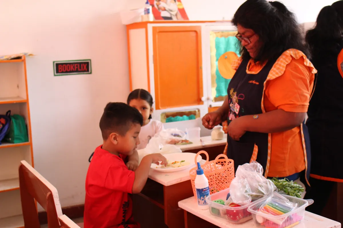 Niño explorando materiales acompañado en un taller del colegio